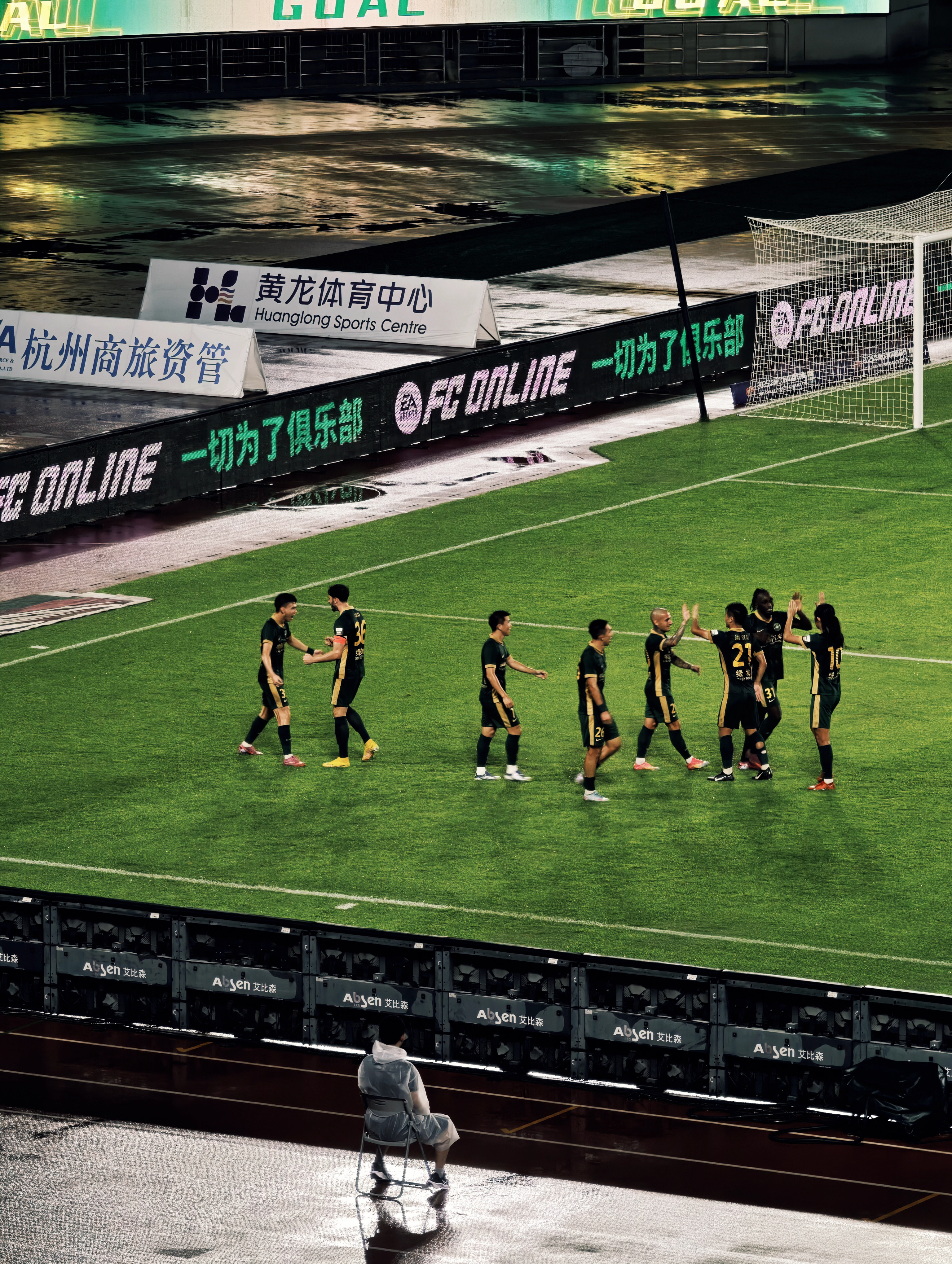 Football players on a green pitch, seen from the stands